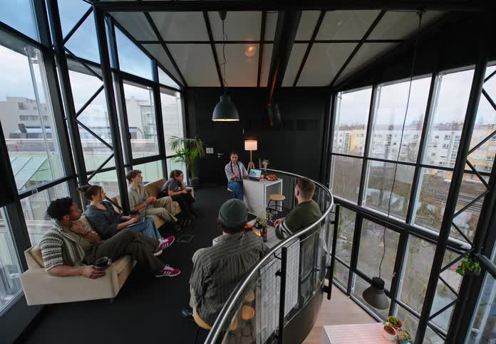 A group of people all sit together on couches in a lofted area of a building