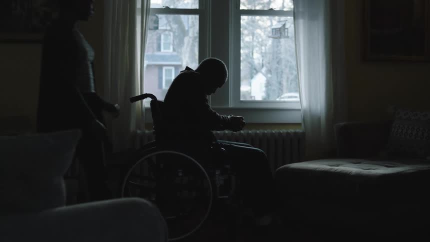 Silhouette of a woman taking care of an elderly person in a wheelchair