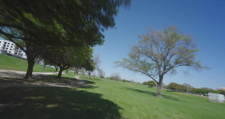 A forward motion shot of a skateboarder and other people in a park