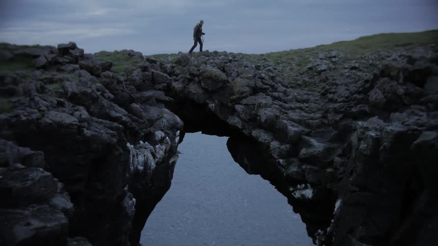 A couple walking on a natura rock bridge over the ocean