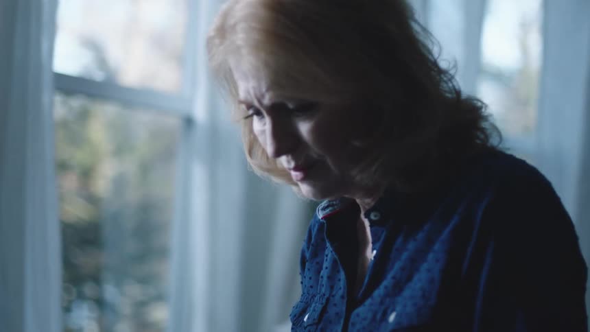 Portrait of a lady picking up an object and looking at it lovingly