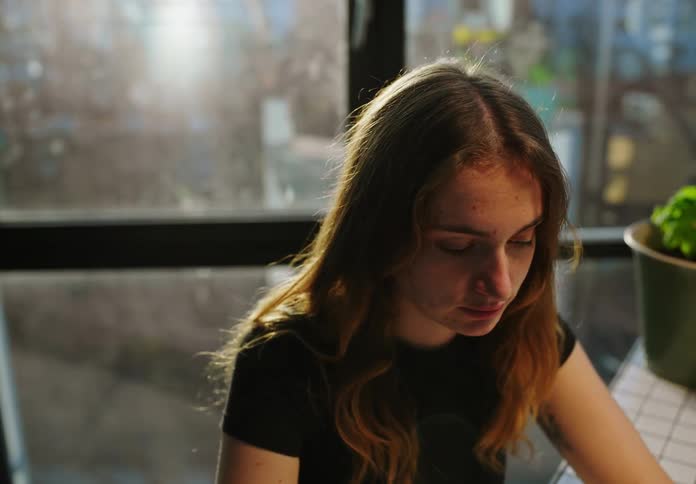 A woman is sitting at a table and drinking a beverage