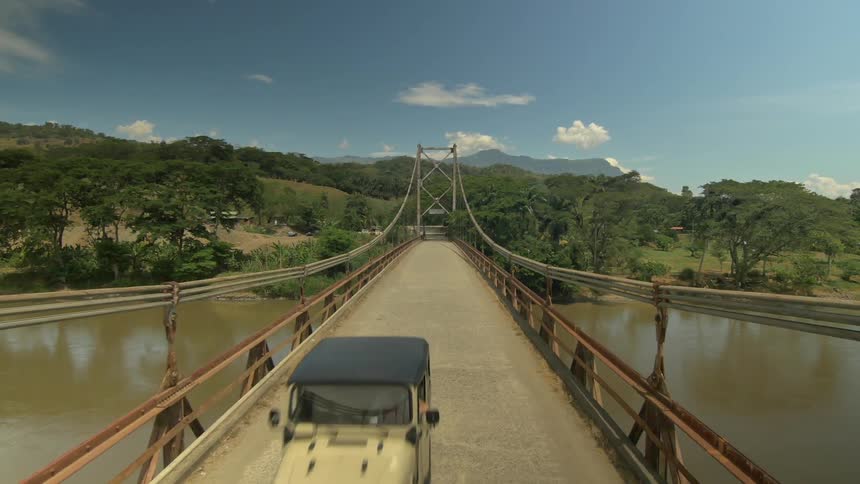 View from the middle of a narrow suspension bridge over a murky waterway