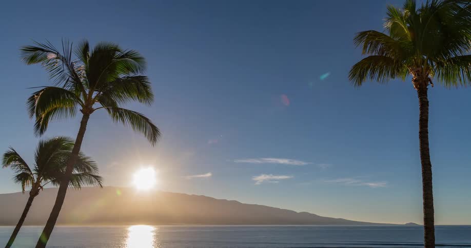 Time lapse of the sun rising over the hillside across the ocean on an island
