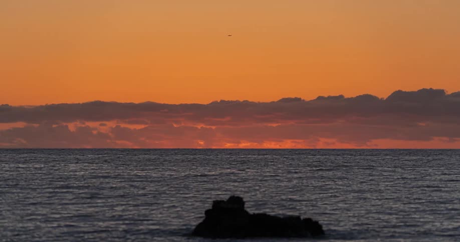 Time lapse of the sun setting through the clouds across the ocean