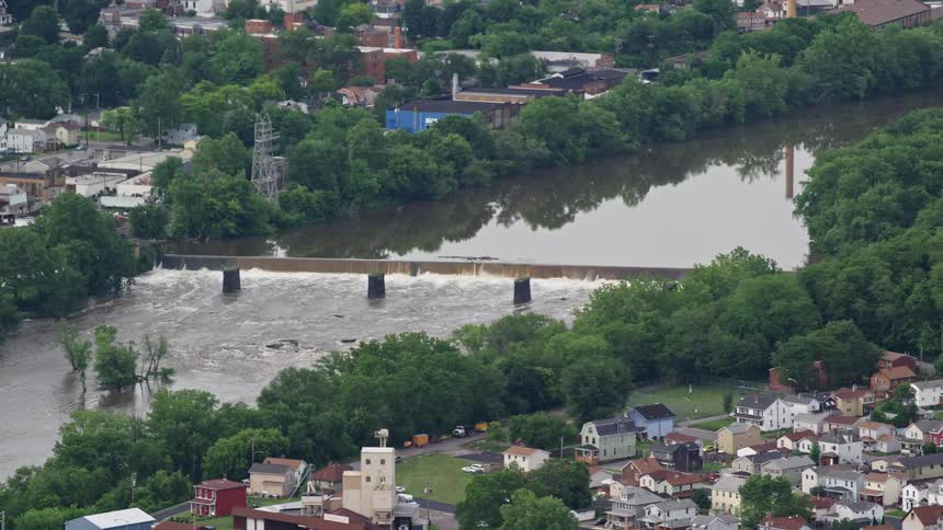 Aerial view of a small dam on a river next to a rural town