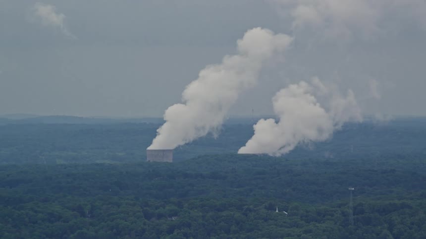 Smoke rises out of two cooling towers in a nuclear power plant set in a forest