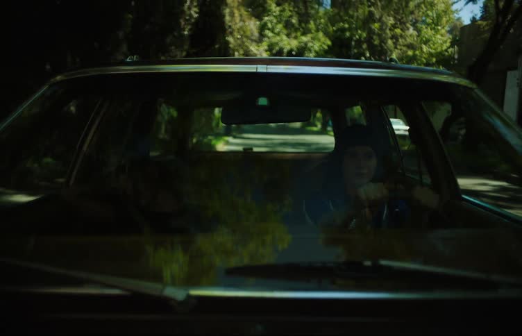 View from the windshield of a woman driving a vehicle and a young girl sleeping next to her