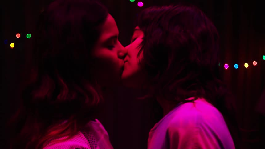 Two young women with their heads touching each other kissing in a room