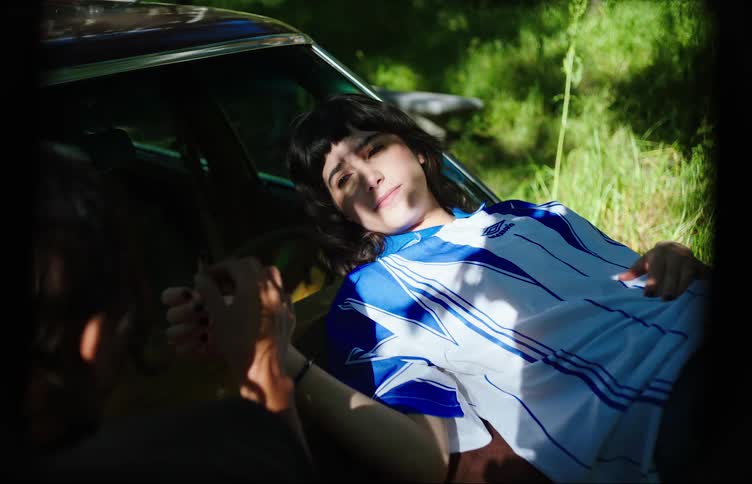 Two teenage girls smoking over the hood of a car