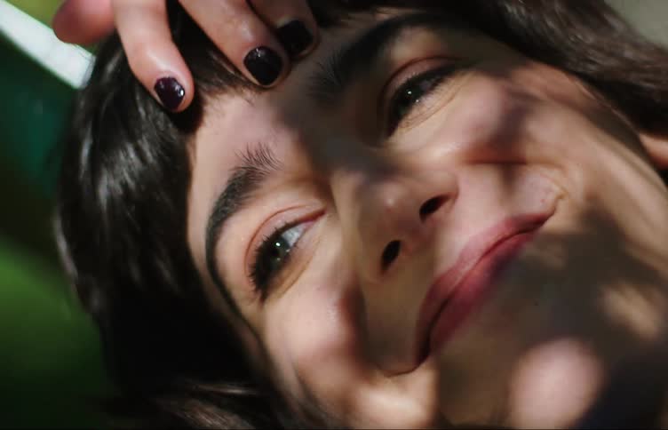 Portrait of a smiling young woman with reflection of tree leaves on her face