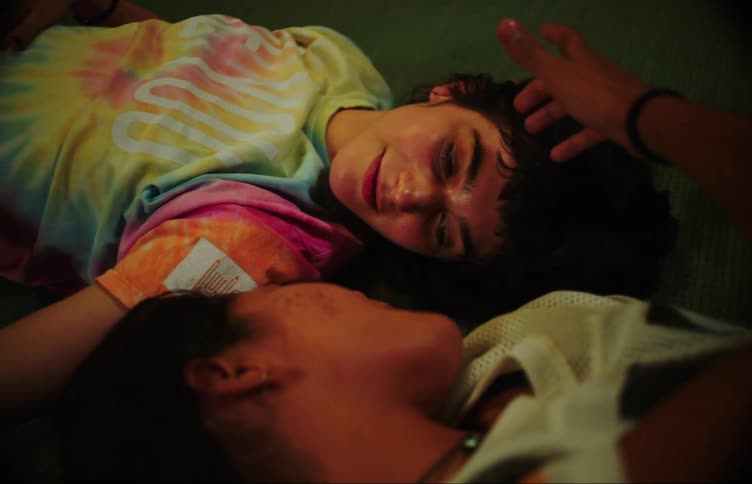 Two young women lying head to head on the floor talking smiling and caressing each other