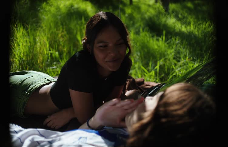 Two teenage girls smoking on the hood of a car