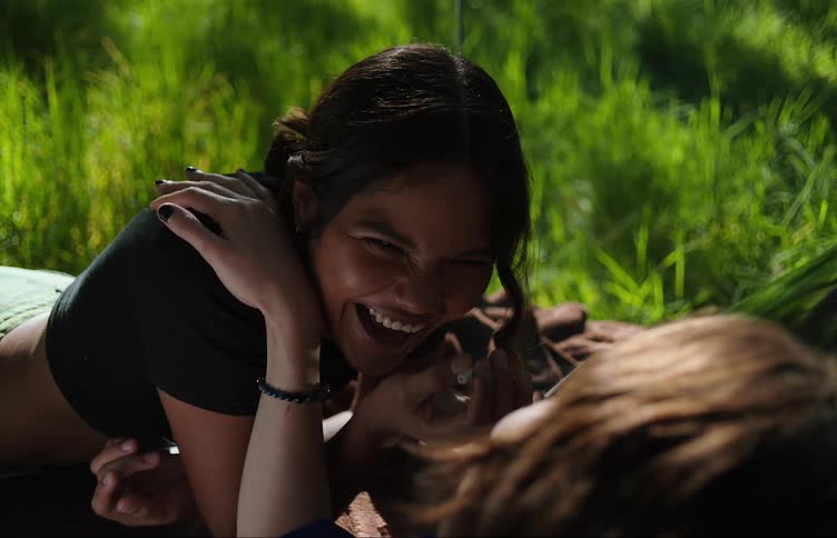 Two friends lying in a natural environment with one of them smoking