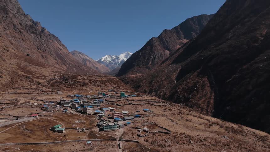 Aerial panorama of a village on a hilltop and surrounded by rocky mountains