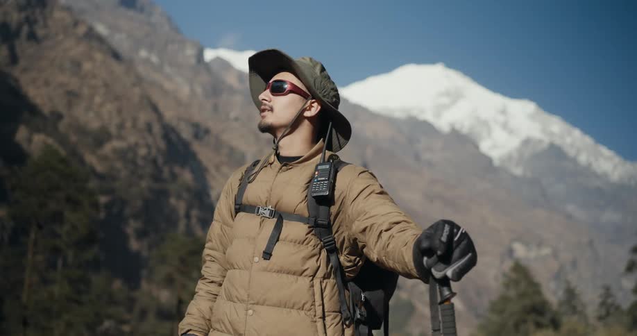 Man with hiking equipment enjoying the view of mountains around him with snow
