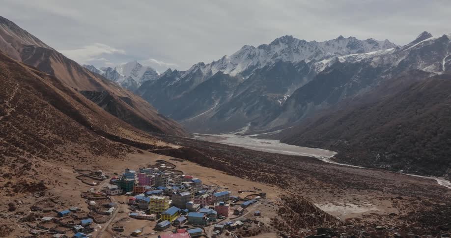 A small town in a mountainous region with snow on top of the mountains