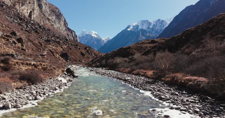 A shallow stream flows through rocky mountains