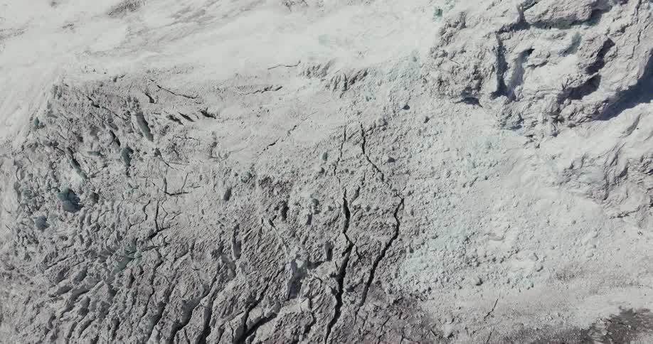 Aerial scenery with downward view of degradation and cracks in snowy geological mountains