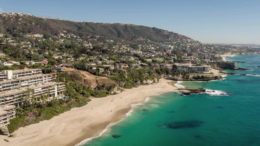 Aerial panorama of a peninsula with the clear blue sea and the coastline with a resort area and urban houses