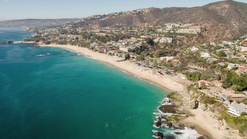 An aerial view of a city beach and the sea water is very blue