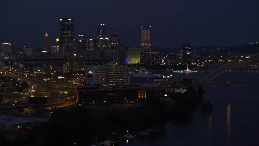 Panorama of a metropolis with a skyscraper by the sea and a bridge interconnecting with vehicle traffic at night