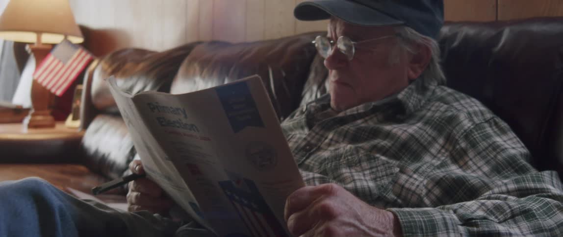 A man is reading a newspaper at home