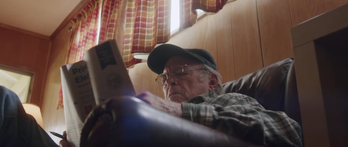 Elderly man sitting concentrated reading his newspaper