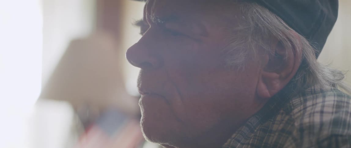 Side portrait of an elderly man sitting thoughtfully taking off his glasses and putting them back on