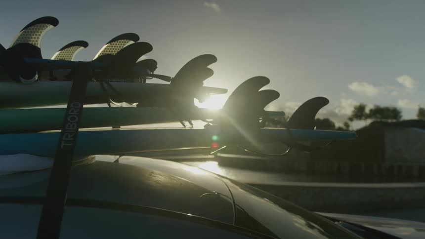 A pile of surfboards strapped to the top of a car