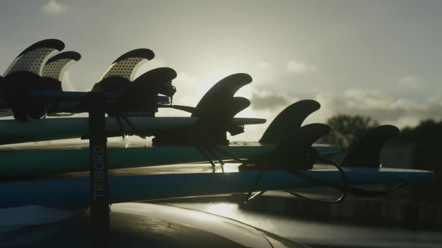 Sun shines behind surfboards piled over a vehicle roof