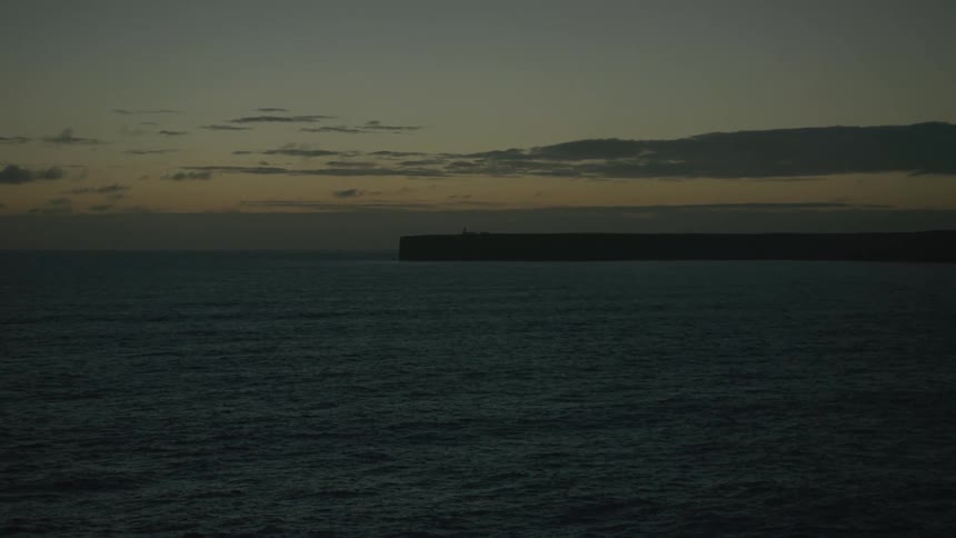 A view of a sea and in the background there is a piece of land in a morning