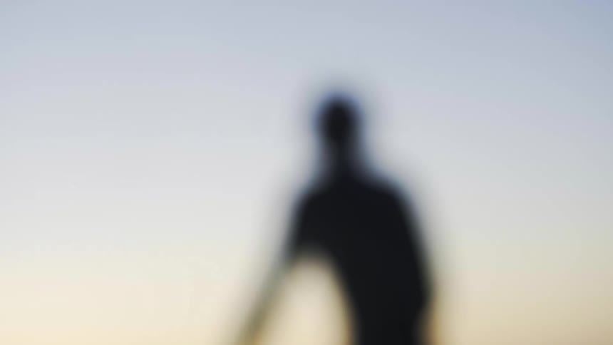 Backwards man sitting on a surfboard in the middle of the sea in a morning sky