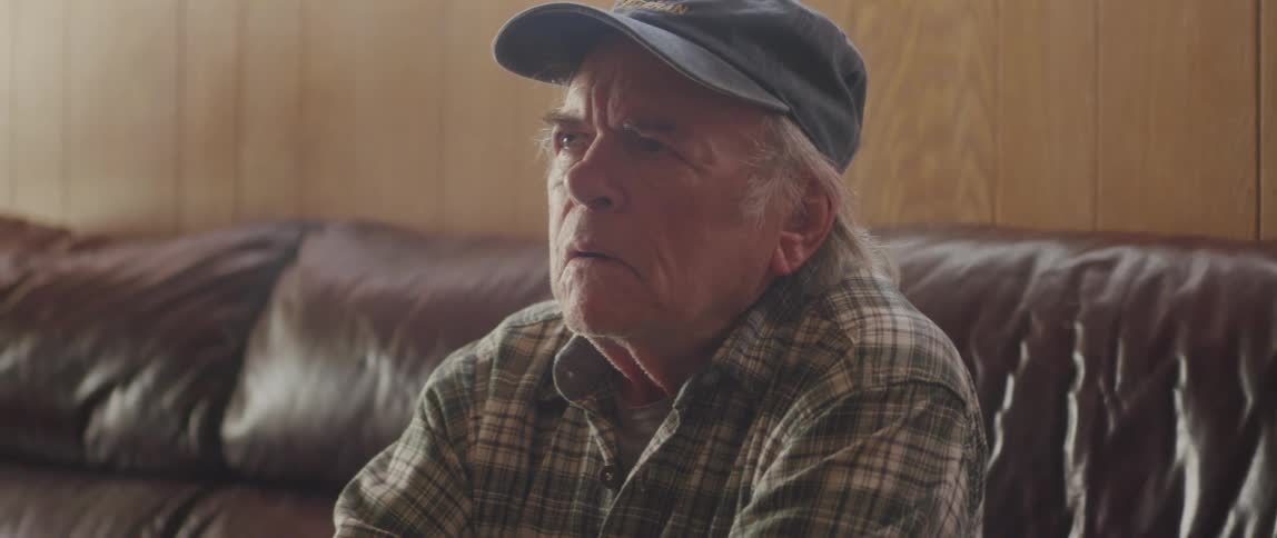 Elderly man in living room looks through election information then sits thinking