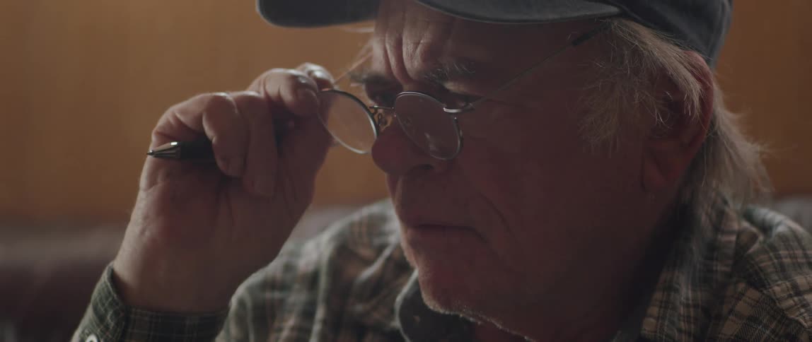 Portrait of an elderly man taking off his glasses while reading a newspaper and thoughtful
