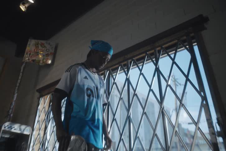 A black man holding a skateboard walks inside a store