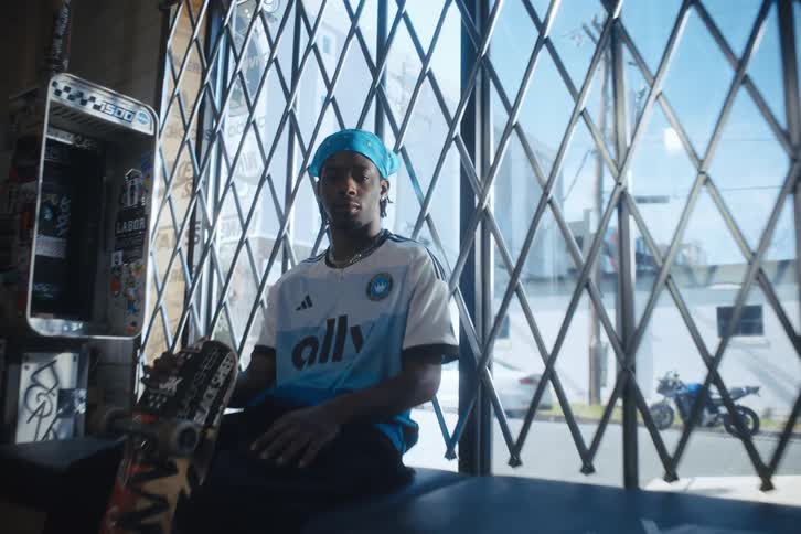 A man is sitting inside holding a skateboard