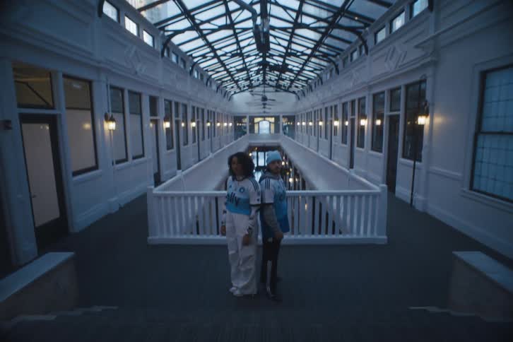 Man and woman in a corridor of a building posing with a tshirt of a football team sponsored by adidas