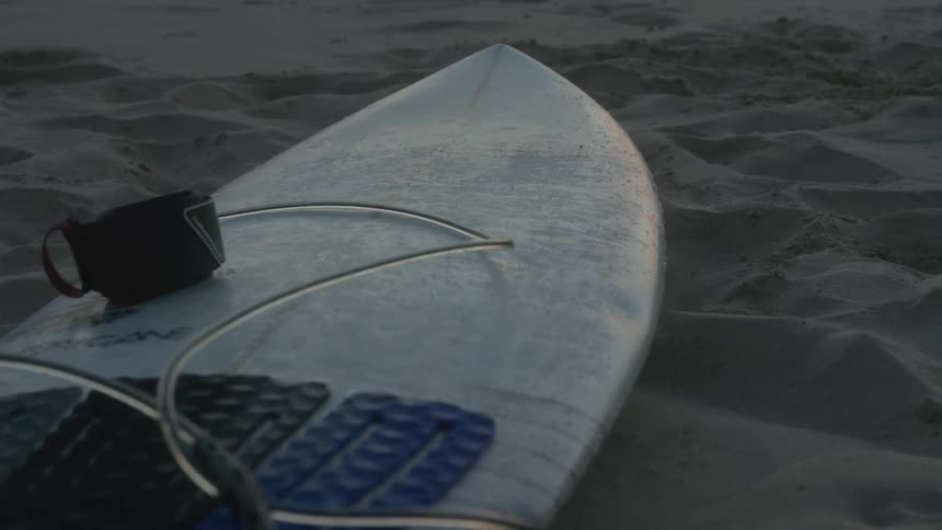 White surfboard laying on the sand at the beach
