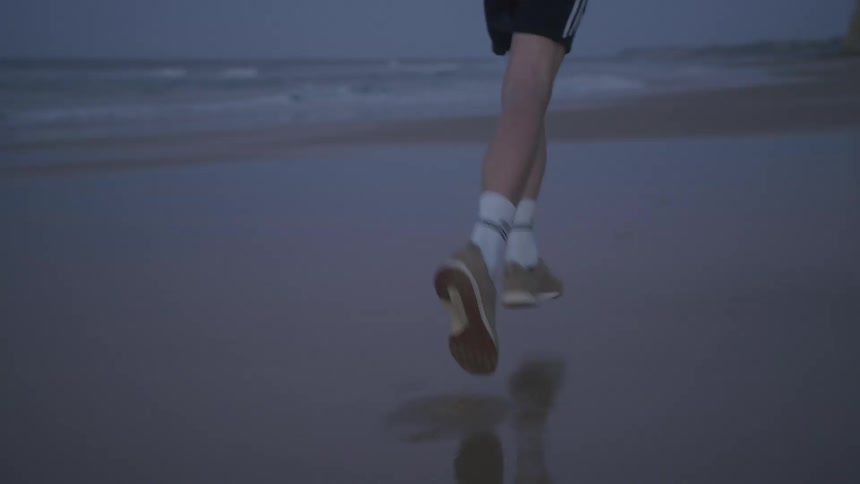 Legs of a man running on the wet beach sand on a morning