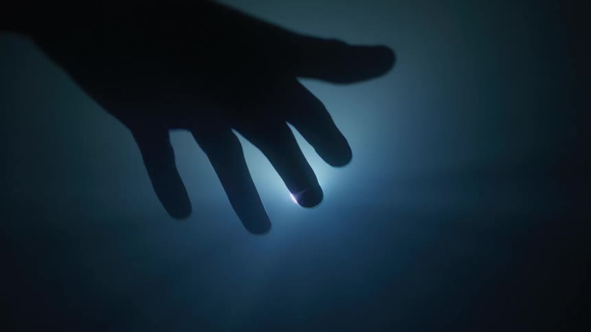 A person moves their hand around a bright light source