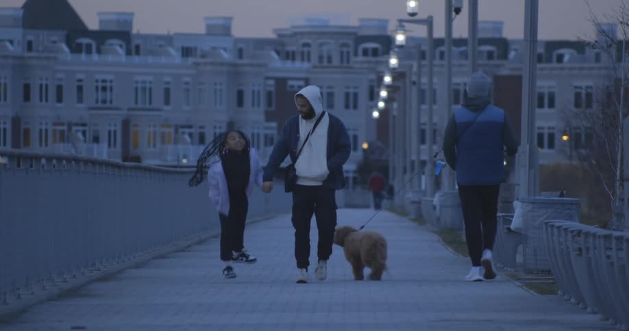 Father and daughter walking on a sidewalk at dusk