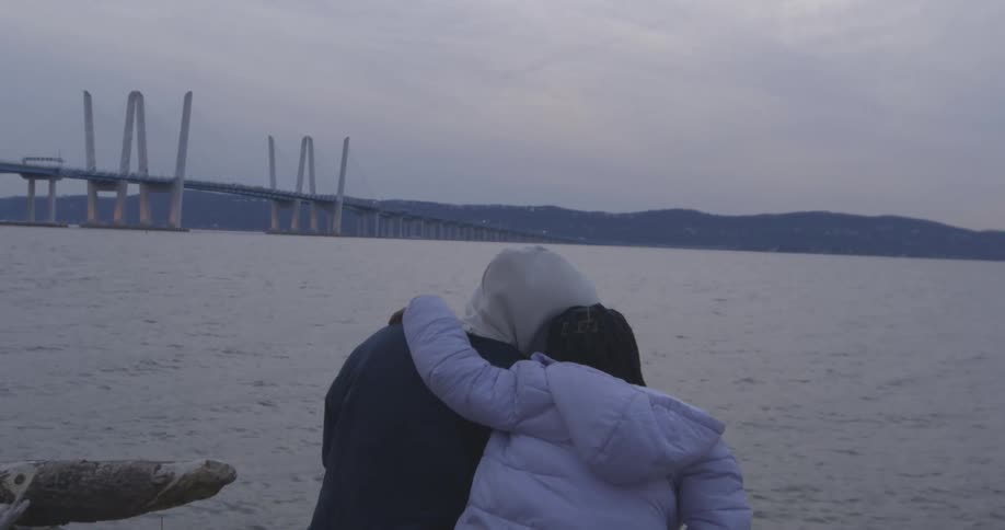 Two people sit by the waterfront
