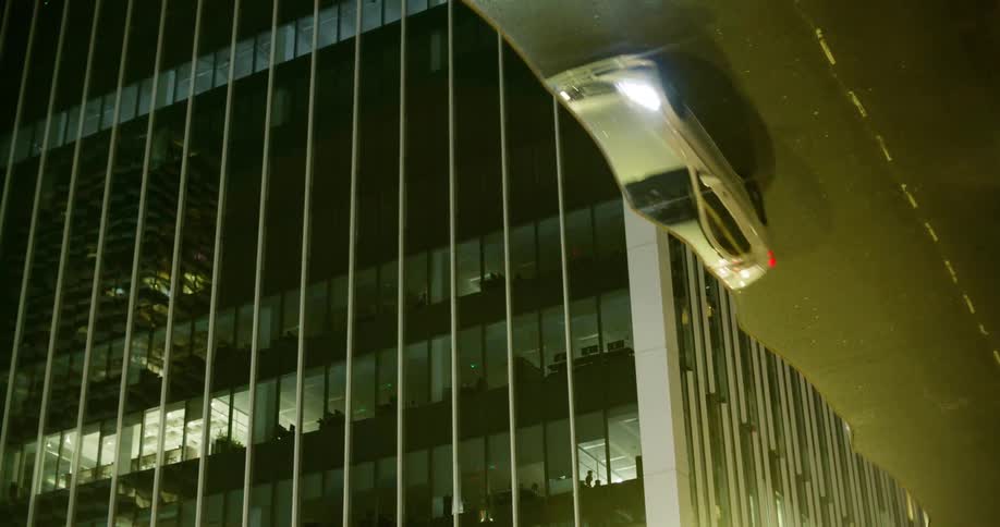 Looking up at an office block as a car, reflected in the roof passes by