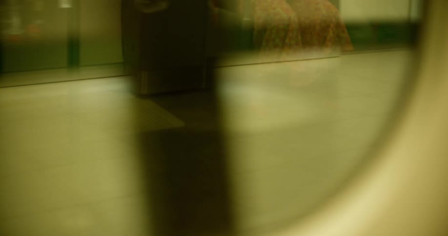 Inside view of a train window inside an underground station with people sitting and standing