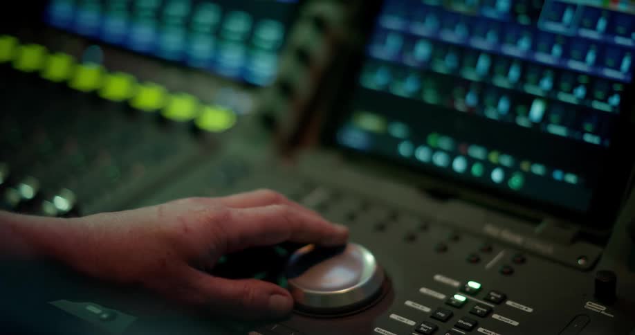 A hand adjusting a a dial on a recording studio mixing desk
