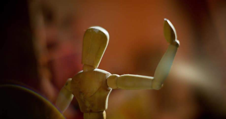 A close up of an artists wooden Mannequin with one arm raised