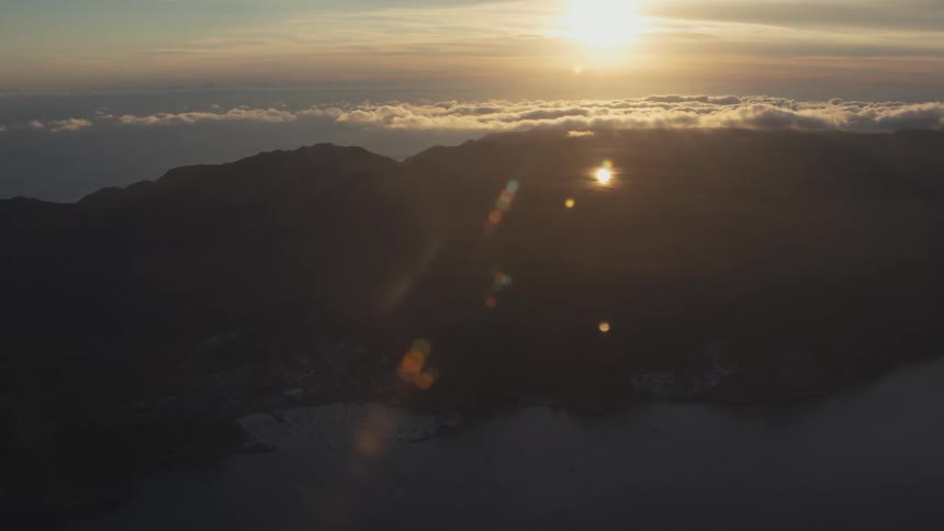 The sun shines over a mountain coastal area