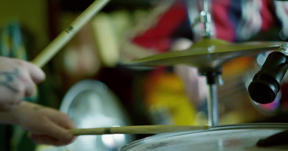 A musician playing the drums with a band at home