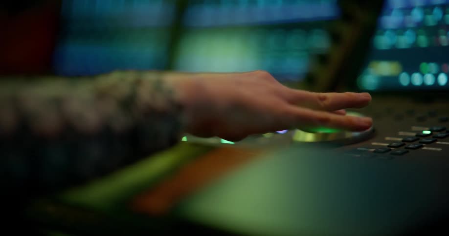 Hands operate a recording studio mixing desk